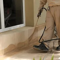 General pest control technician spraying exterior perimeter around a home in Shreveport, LA