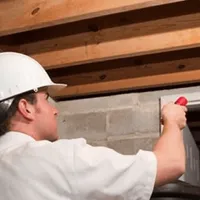 Termite inspection technician checking a basement wall and framing for termite activity in Shreveport, LA